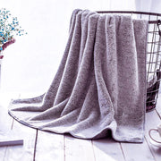 Seisso purple towel draped over a wire basket on a light wooden floor.